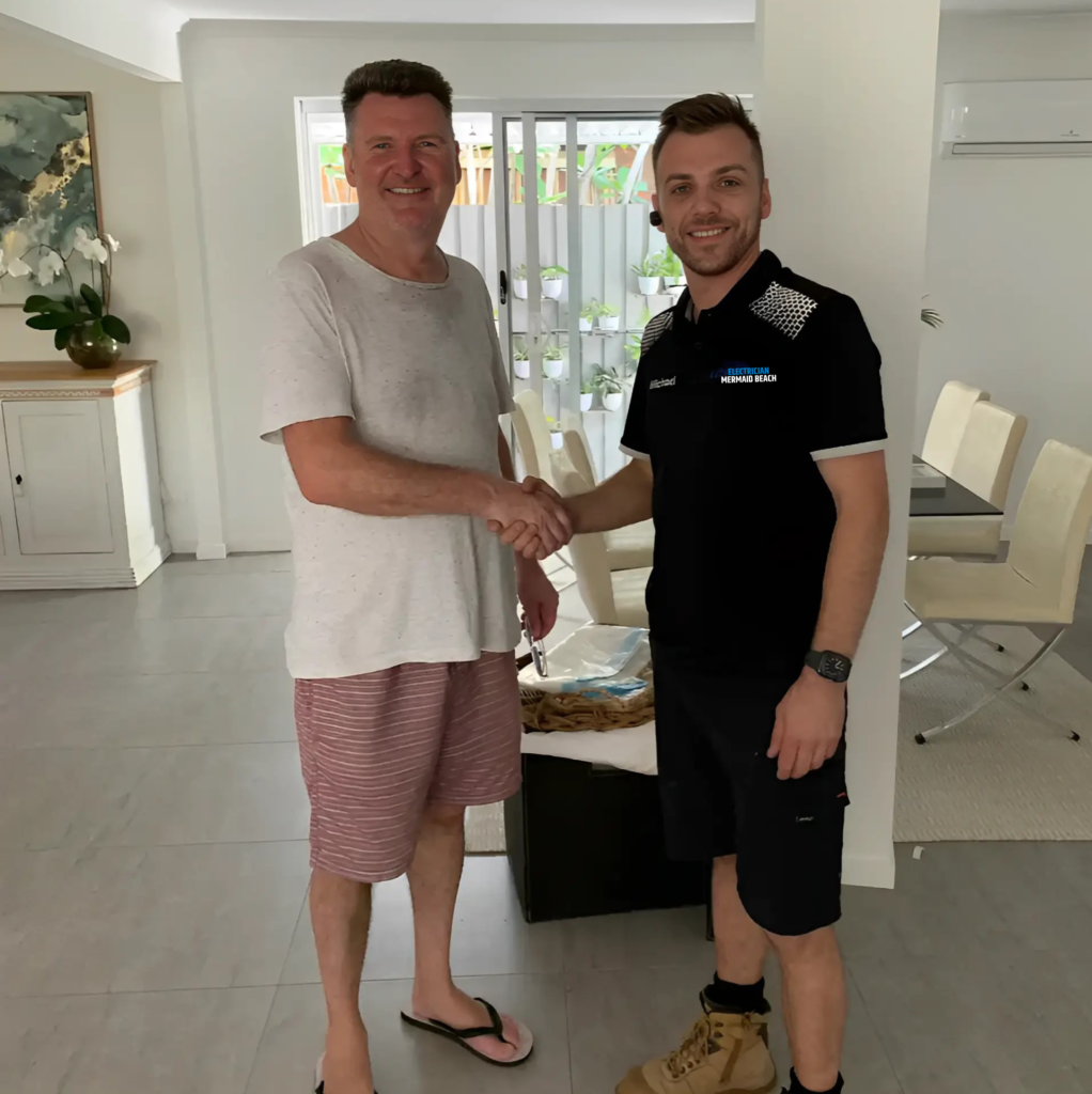 Electrician shaking hands with a client in a home interior, both smiling